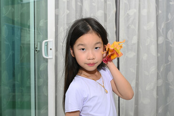 Portrait of a cute little Asian girl with a colourful cattleya orchid