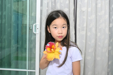 Portrait of a cute little Asian girl with a colourful cattleya orchid