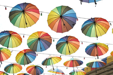 Colorful umbrella hanging on a wire on a white background