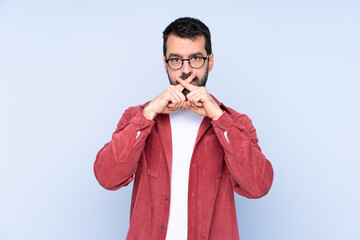 Young caucasian man wearing corduroy jacket over blue background showing a sign of silence gesture