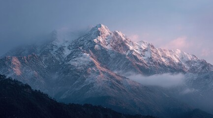 Snowy mountain peak at dawn.  Sunrise hues paint the majestic, snow-capped peak against a backdrop of misty mountains and valleys
