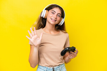 Young caucasian woman playing with a video game controller isolated on yellow background counting...