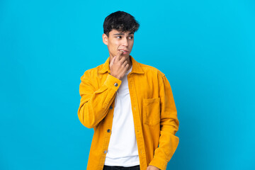 Young man over isolated blue background nervous and scared