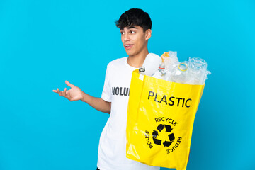 holding a bag full of plastic bottles to recycle over blue background with surprise expression...