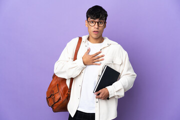 Young student man over isolated purple background surprised and shocked while looking right