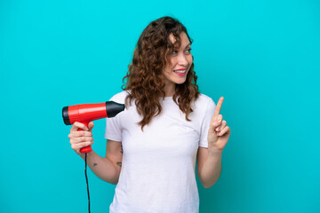 Young caucasian woman holding a hairdryer isolated on blue background intending to realizes the...