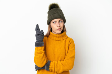Young girl with winter hat isolated on white background with fingers crossing and wishing the best