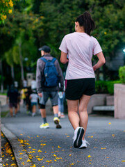 Obraz premium People Running and Walking Exercise in Lush Green Public Park with Shade Trees - Outdoor Fitness Activity.