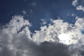 Sun shining through dramatic clouds in deep blue sky