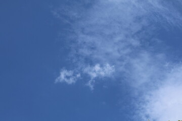 Wispy white clouds drifting across a vibrant blue sky