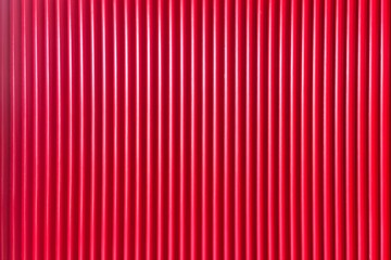 Vibrant red corrugated metal texture with vertical ridges, ideal for industrial design, architectural backgrounds, and graphic overlays. This seamless pattern offers a bold, modern aesthetic suitable 