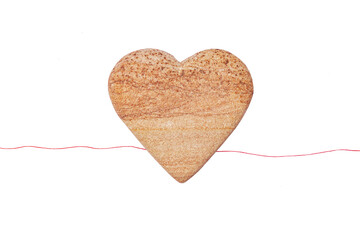 Red spool of yarn and stone heart shaped on white background