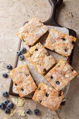 Soft and moist blueberry almond cake closeup on the wooden board on the table. Vertical top view from above