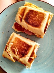 Toast with ham and cheese on blue plate. Toned.