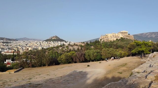 View of Pnyx Hill in Athens, Greece the historic gathering place of ancient democratic assemblies, with the majestic Parthenon and the iconic Lycabettus Hill rising gracefully in the background.