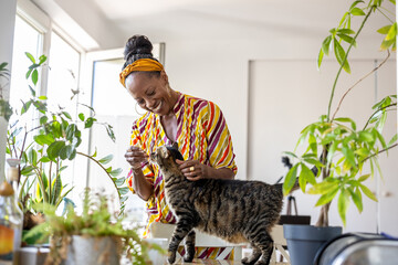 Portrait of smiling woman with her cat at home
