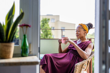 Woman drinking coffee at home balcony

