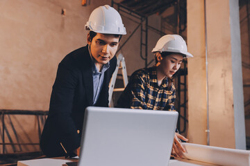 Construction manager and engineer dressed in orange work vests and hard helmets explore...