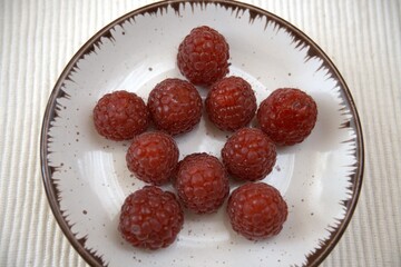 Fresh raspberries served on a small plate. Close up view with shallow depth of field.