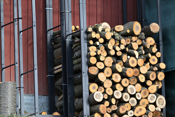 Wood for the winter stored in iron decorative racks against the wall of the house