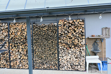 Wood for the winter stored in iron decorative racks against the wall of the house