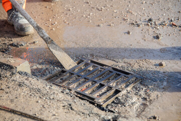 Builders opening blocked road gully for cleaning to prevent street flooding