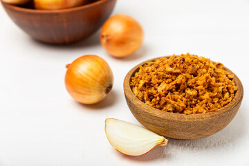 Crispy fried onions in a bowl on a wooden table. Roasted Onions. Seasoning for dishes. Spices....