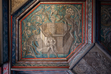Close-up photograph of a medieval painted wooden ceiling panel depicting a symbolic scene with a fountain and a female figure. 