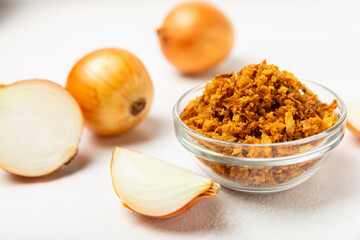Crispy fried onions in a bowl on a wooden table. Roasted Onions. Seasoning for dishes. Spices. Salad dressing. Space for text. Copy space