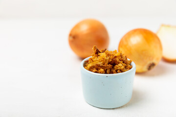 Crispy fried onions in a bowl on a wooden table. Roasted Onions. Seasoning for dishes. Spices. Salad dressing. Space for text. Copy space