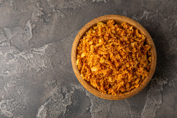 Crispy fried onions in a bowl on a wooden table. Roasted Onions. Seasoning for dishes. Spices. Salad dressing. Space for text. Copy space