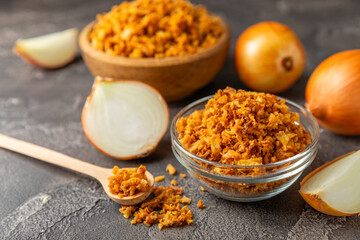 Crispy fried onions in a bowl on a wooden table. Roasted Onions. Seasoning for dishes. Spices....