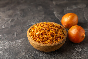Crispy fried onions in a bowl on a wooden table. Roasted Onions. Seasoning for dishes. Spices. Salad dressing. Space for text. Copy space