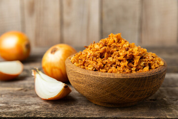 Crispy fried onions in a bowl on a wooden table. Roasted Onions. Seasoning for dishes. Spices....