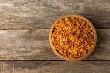 Crispy fried onions in a bowl on a wooden table. Roasted Onions. Seasoning for dishes. Spices....