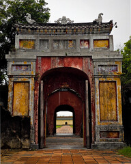 Ancient yellow and red gate of Hue Imperial Citadel in Vietnam with ornate tiled roof.