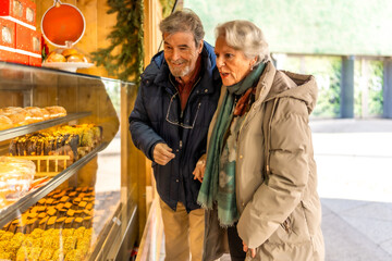 Senior couple choosing pastries at christmas market