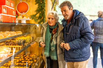 Senior couple choosing christmas cakes at outdoor market