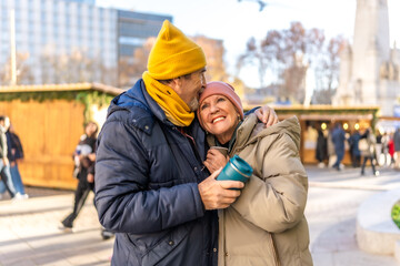 Happy senior couple embracing at christmas market in winter city