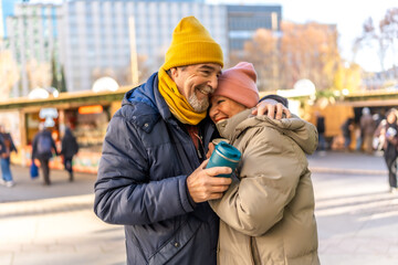 Happy senior couple embracing at christmas market in winter city