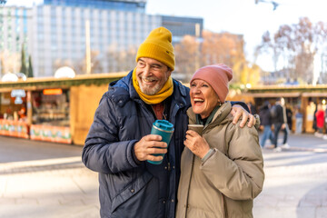 Happy senior couple drinking hot beverages at christmas market