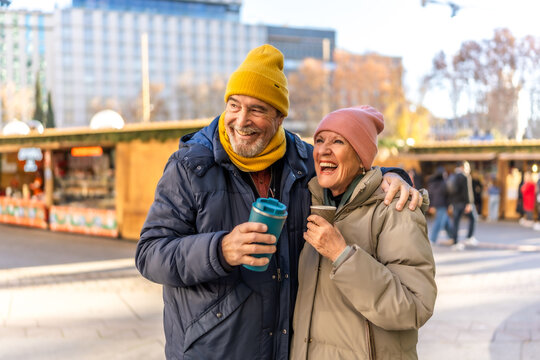 Happy senior couple drinking hot beverages at christmas market