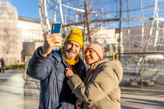Happy senior couple taking selfie in winter city center - Powered by Adobe