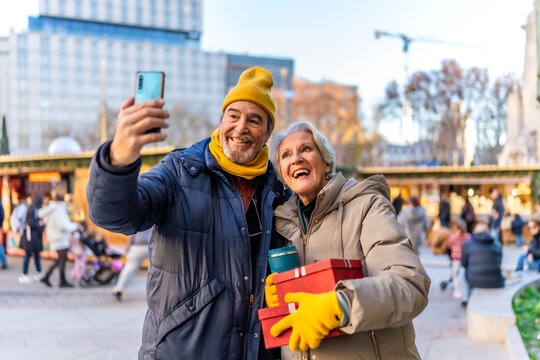 Happy senior couple taking selfie at christmas market in the city - Powered by Adobe