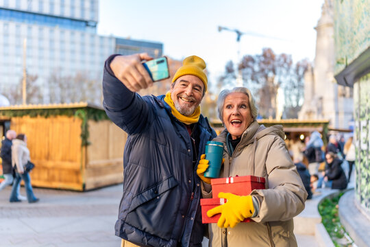 Happy senior couple taking selfie at christmas market in winter city - Powered by Adobe