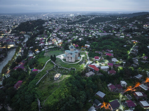 Aerial view of Bagrati Cathedral standing majestically atop Ukimerioni Hill, overlooking the Rioni River winding through the city, Kutaisi, Imereti, Georgia.