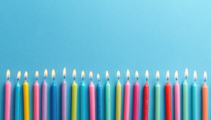 Colorful birthday candles, lit, against a vibrant light-blue background