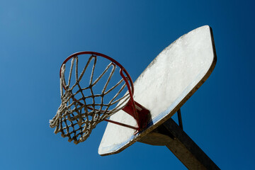 Basketball hoop under a clear blue sky at a neighborhood park during daytime © JBN