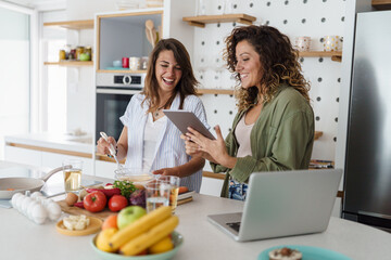 Young Happy Women Friends Cooking Together in a Bright Modern Kitchen with Fresh Ingredients