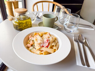 Pasta dish with vegetables and cheese served with herbal tea in cafe. Dining moment symbolizing nutrition, lifestyle and gourmet cuisine culture.